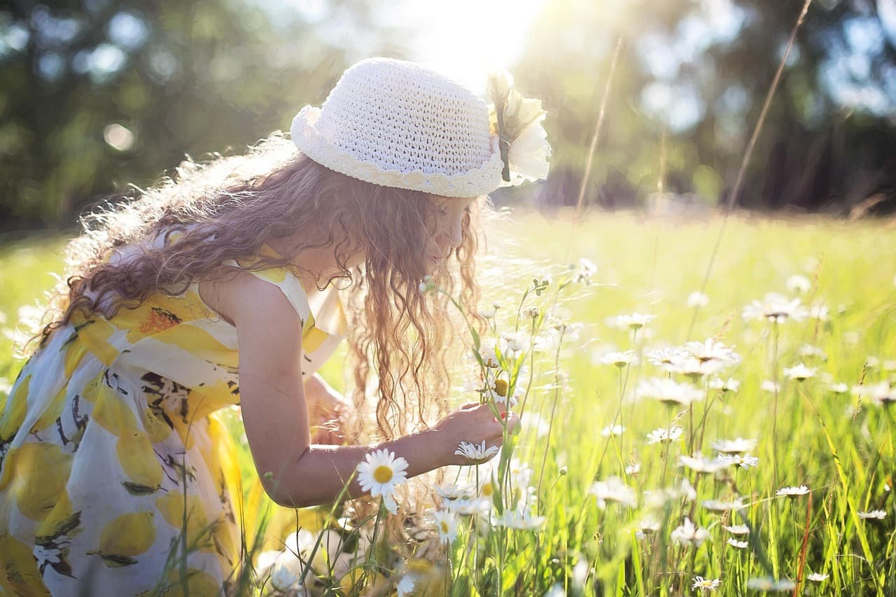 Child playing happily outdoors in summer garden with flowers and sunshine in the background