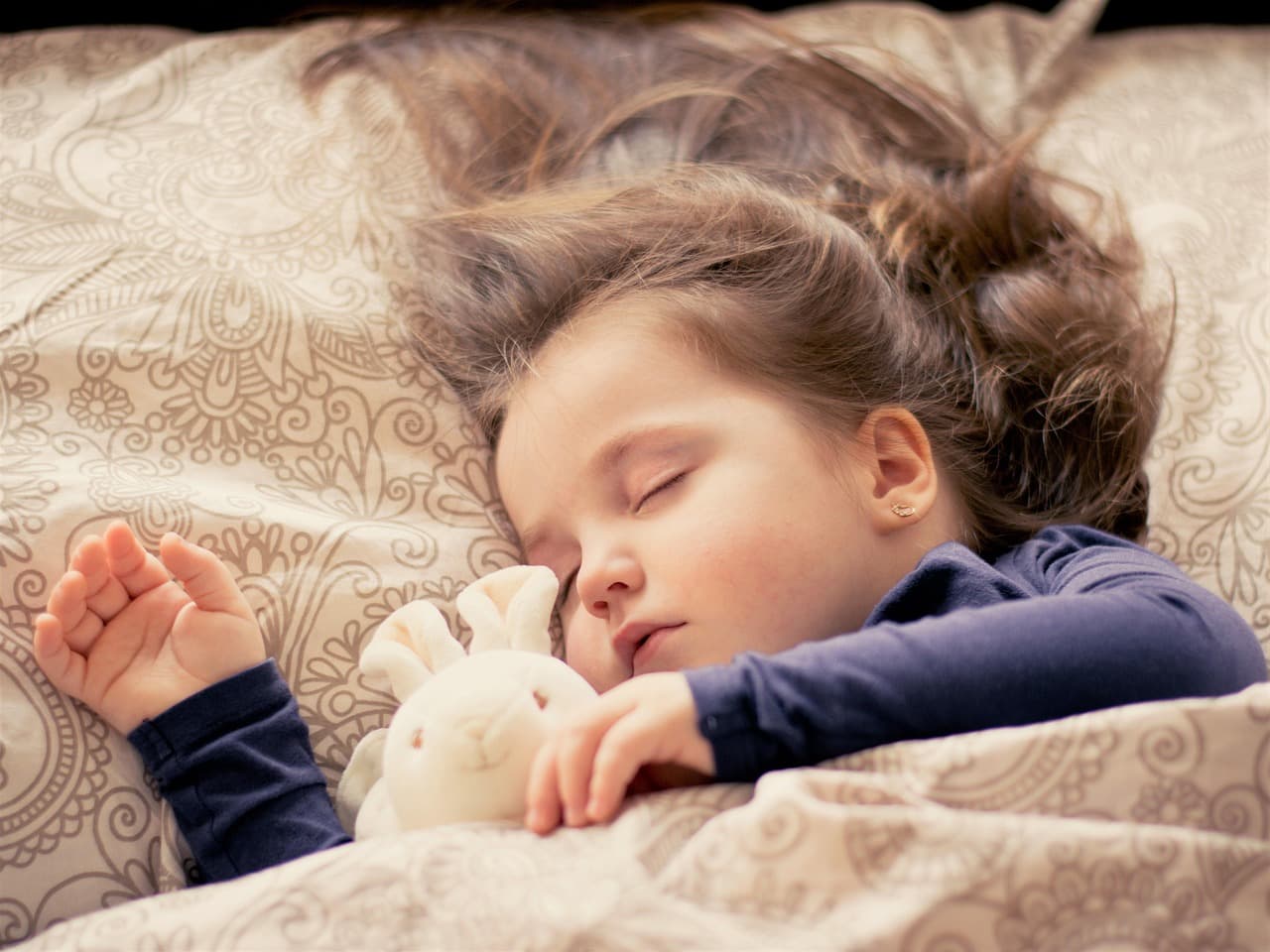Child sleeping peacefully in a cozy bed, bedroom with warm lighting at night