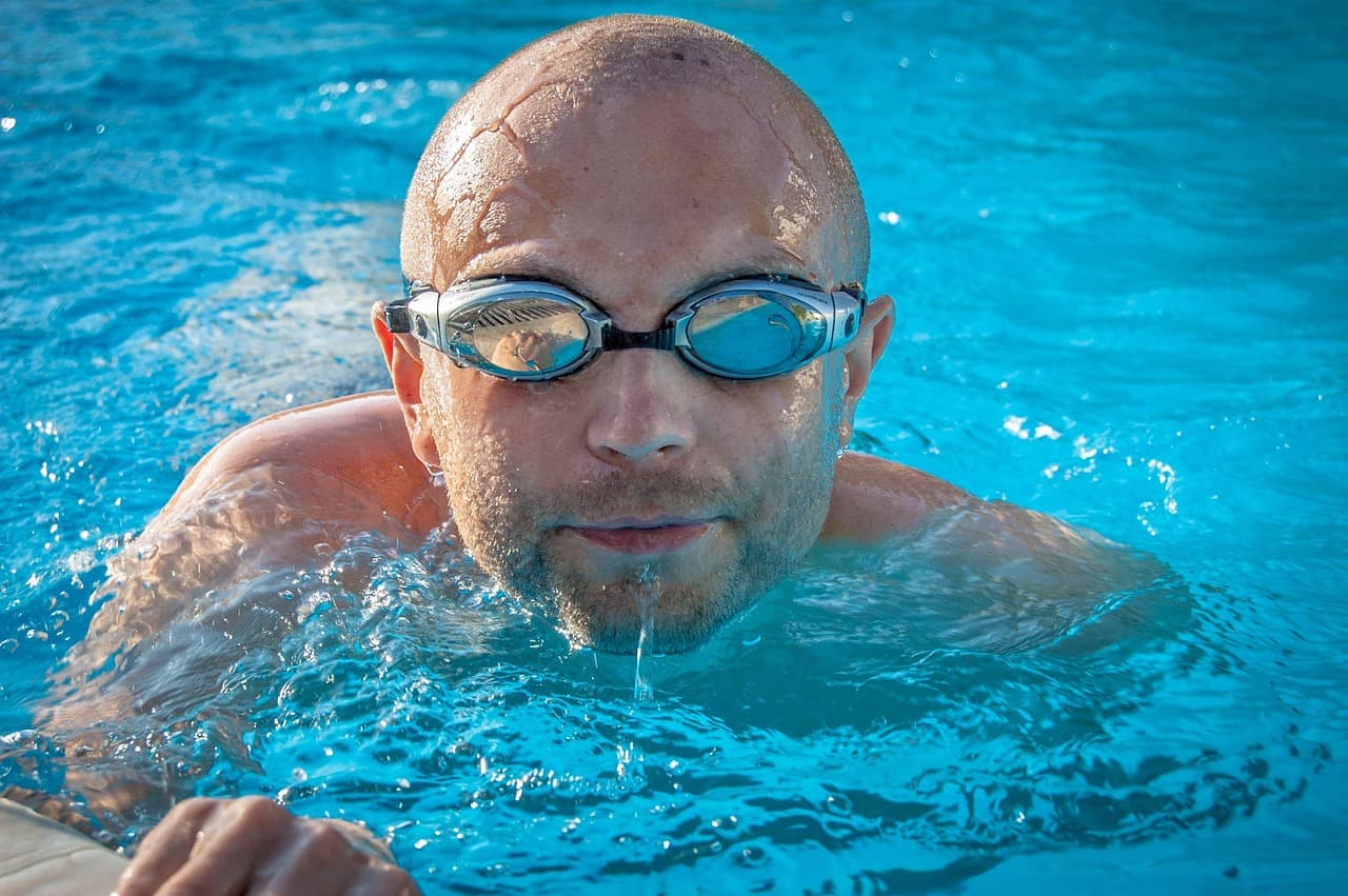 Child holding ear in pain near swimming pool - swimmer's ear otitis externa