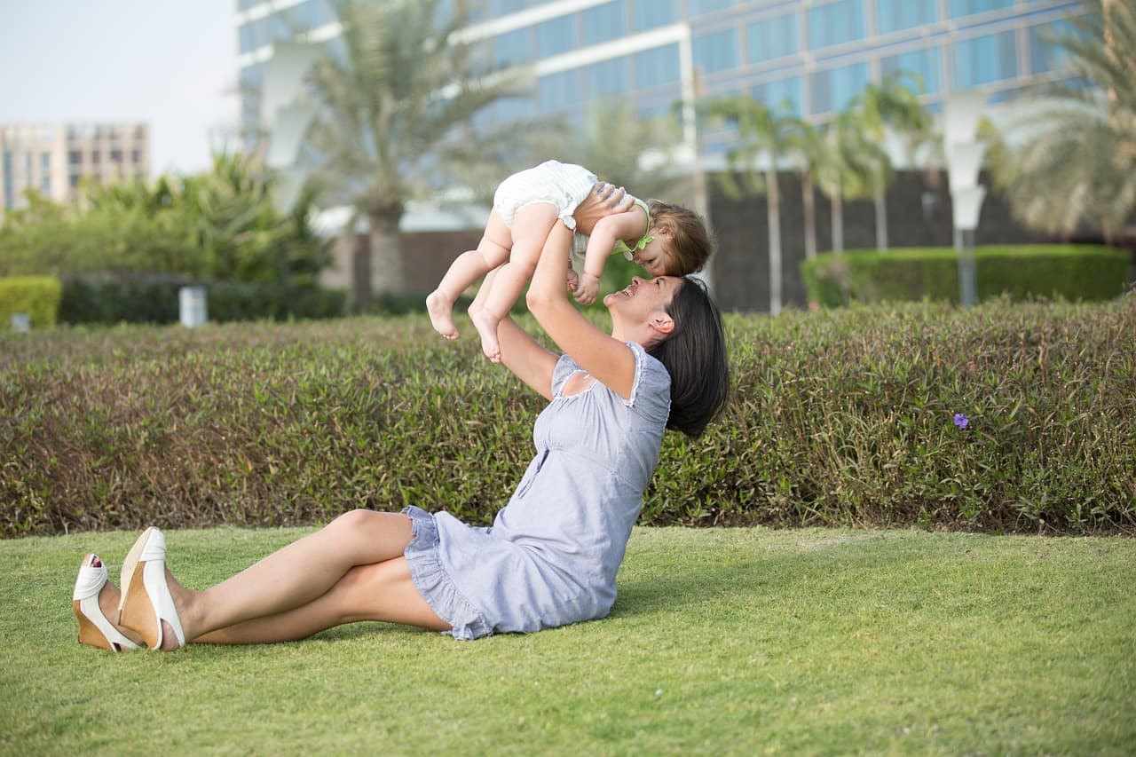 Parent checking child's hair and neck for ticks after outdoor play in grassy area