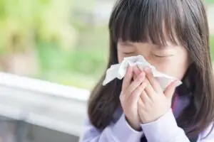 little girl blowing her nose.