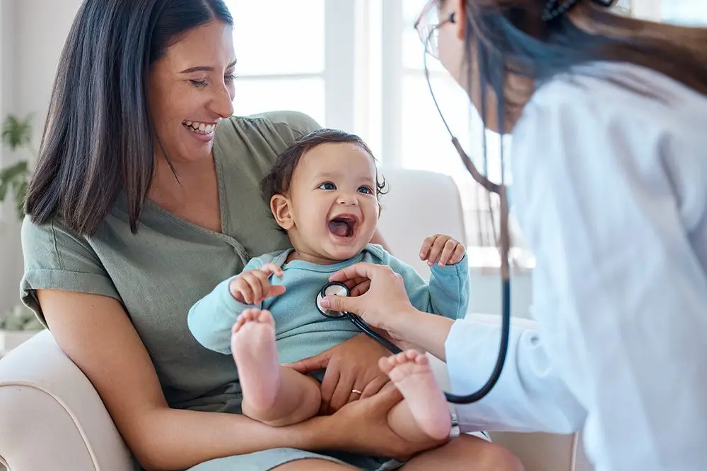 pediatrician checking baby's heart while his mother holds him on her lap