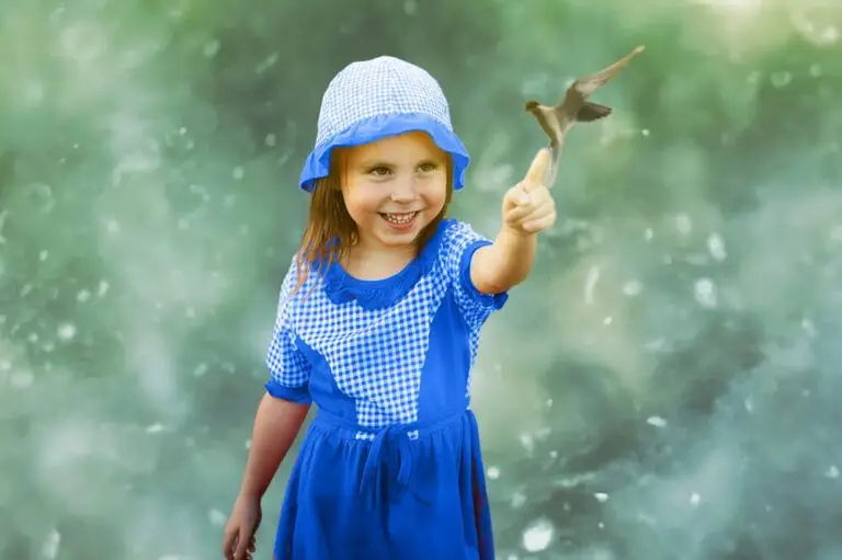 young girl holding hand out to touch hummingbird